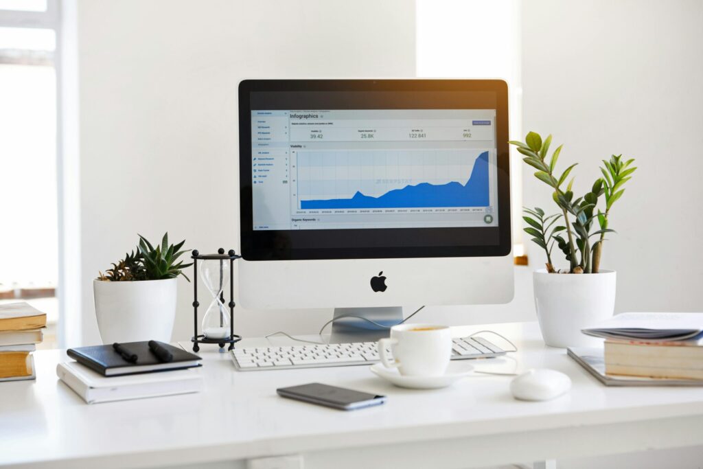 pexels photo 572056 572056 A clean, contemporary workspace featuring a desktop with analytics on the screen and plants for a fresh look.