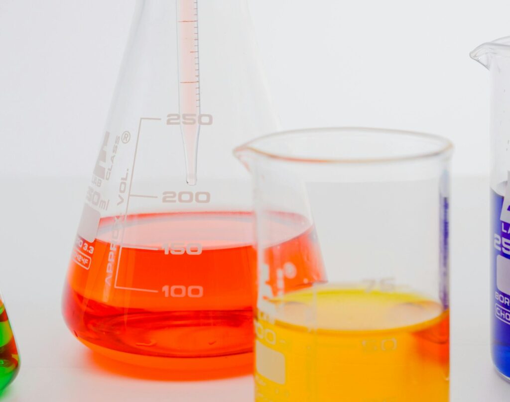 Vibrant lab setup with Erlenmeyer flask and beaker containing colored liquids.